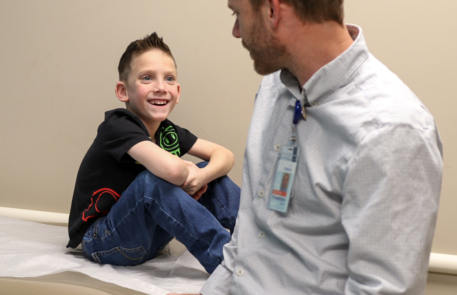 Child sitting on doctors table smiling at doctor