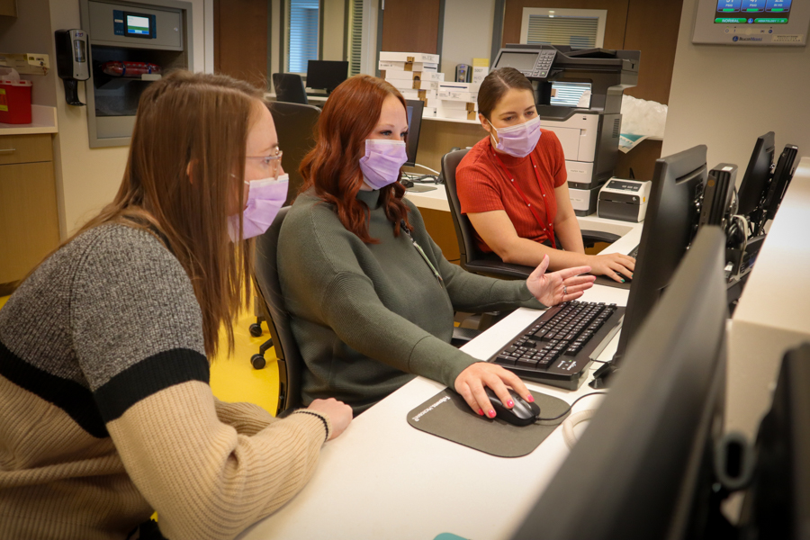 fellows sitting at a desk looking at a computer