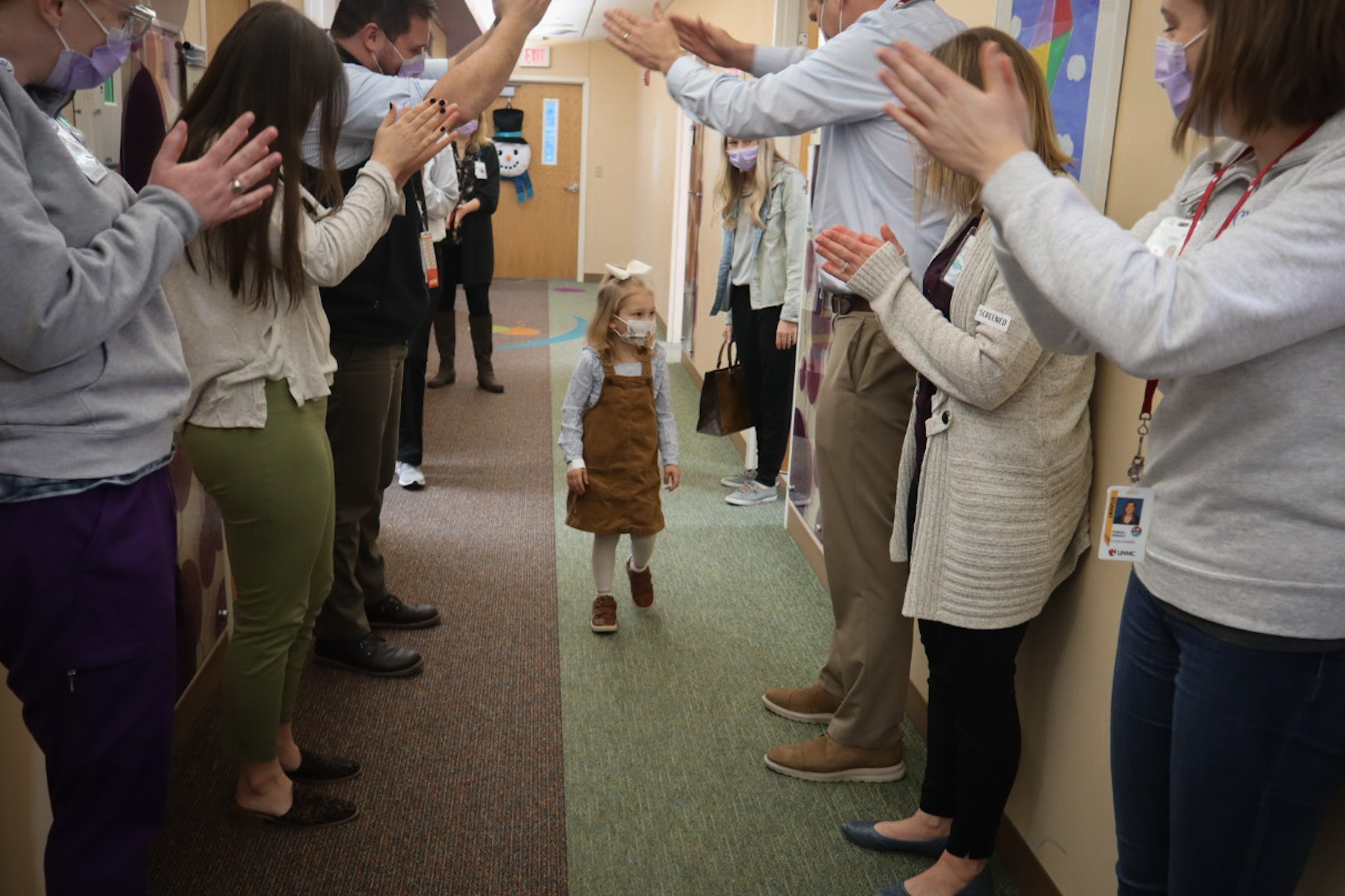 girl walks down clinical hallway as people cheer