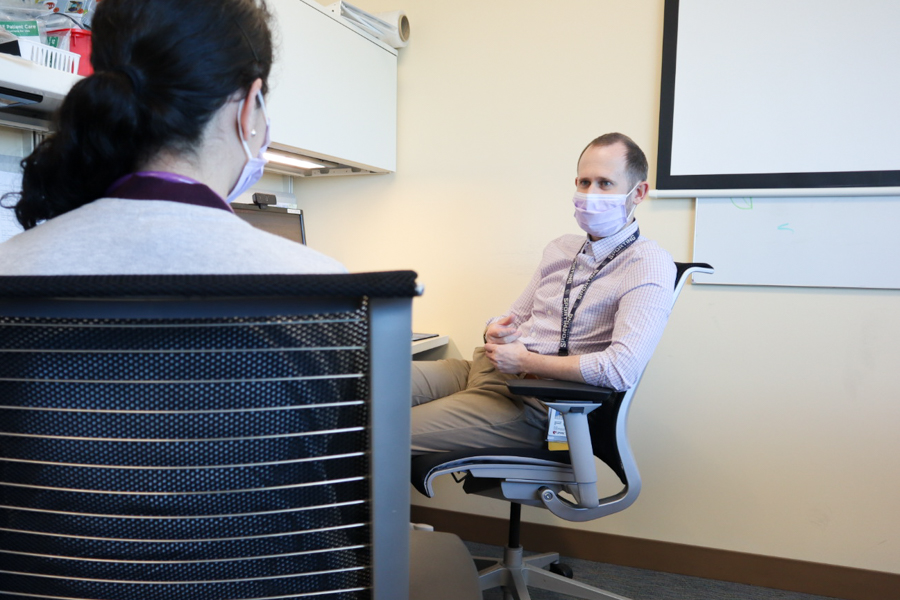 Fellow seated in chair talking to attending