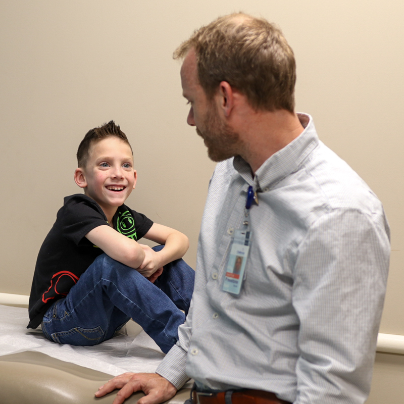 Gastroenterology patient sitting on exam table smiling at doctor