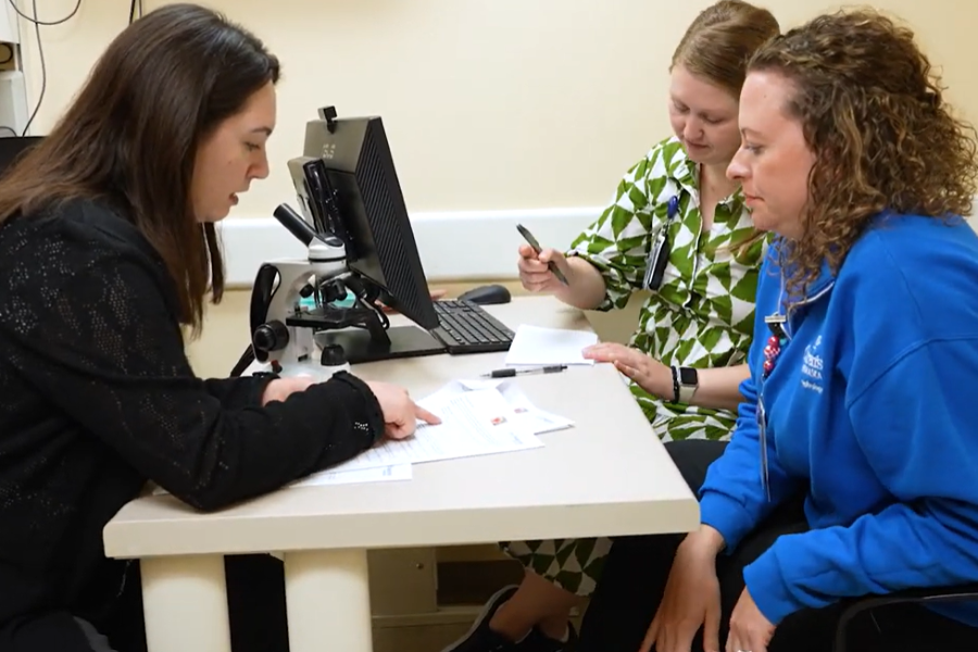 three people sit at a table looking at document