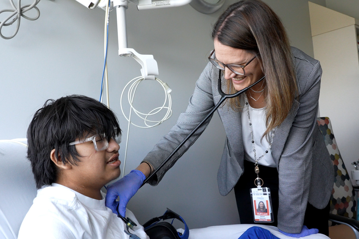 doctor treating pediatric patient in clinical office with fellow in background