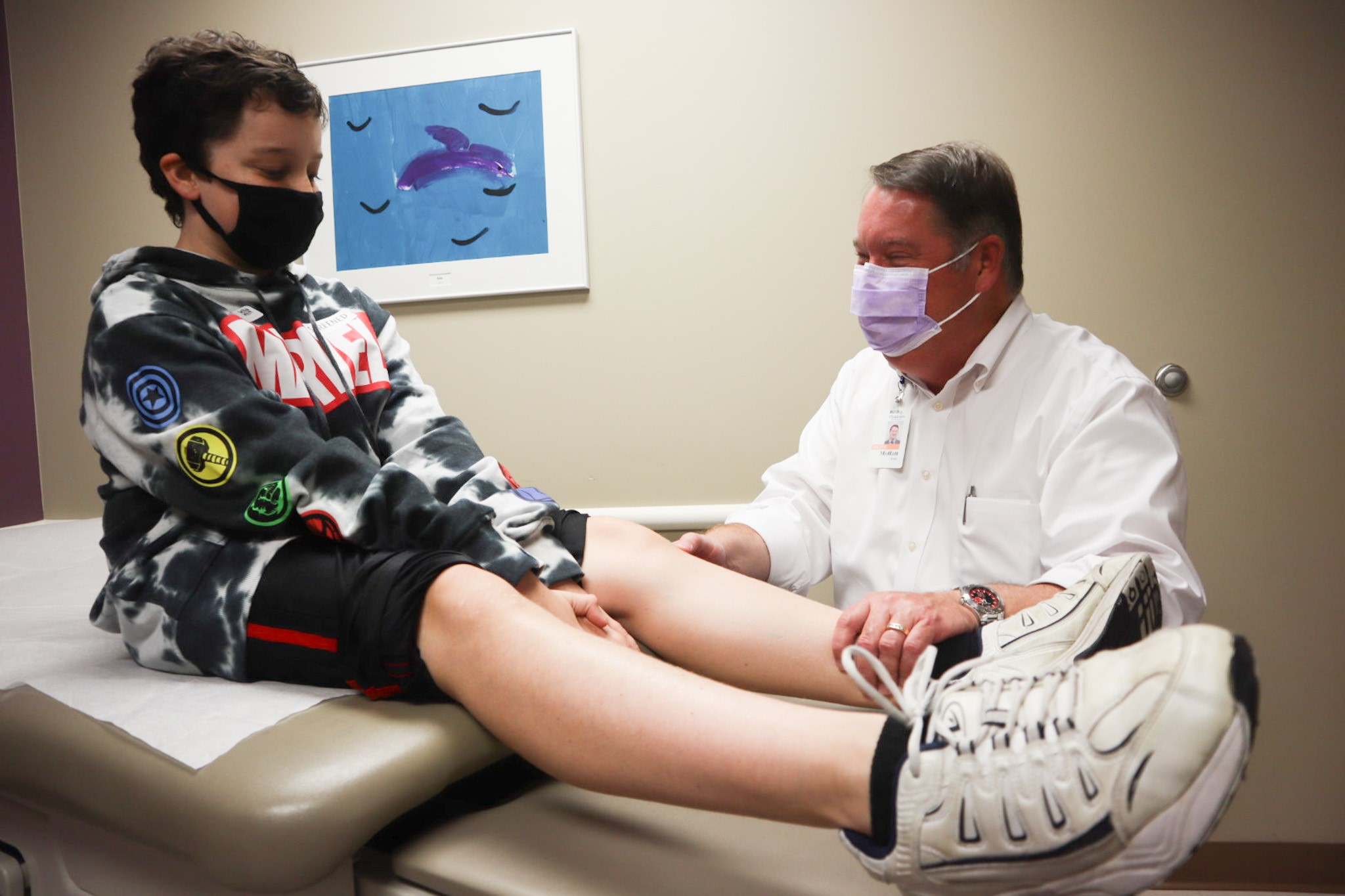 Doctor examining child sitting on table in doctor's office.