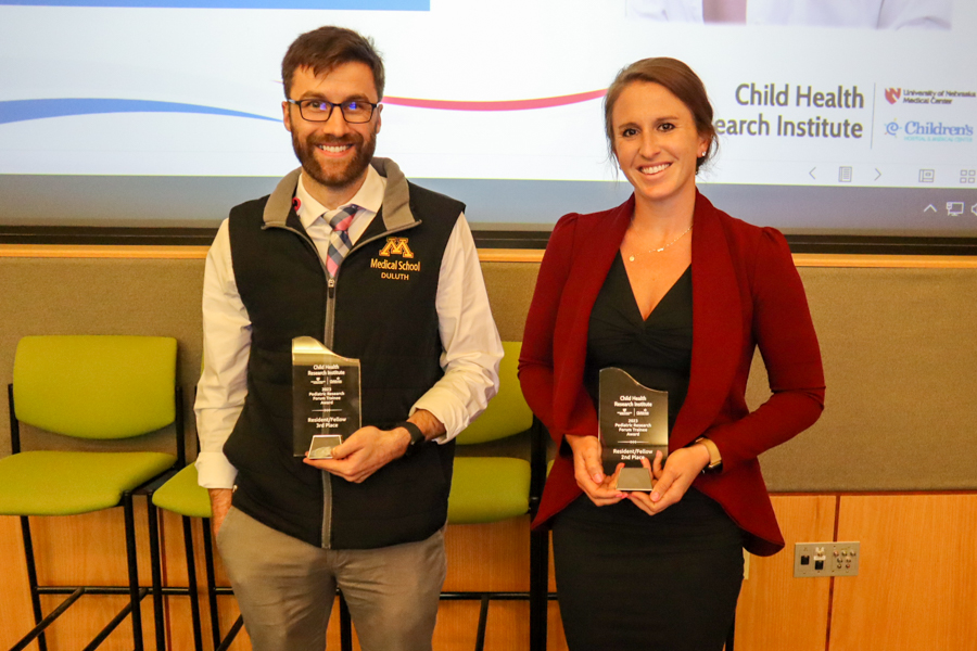 Male and female fellow holding research awards.