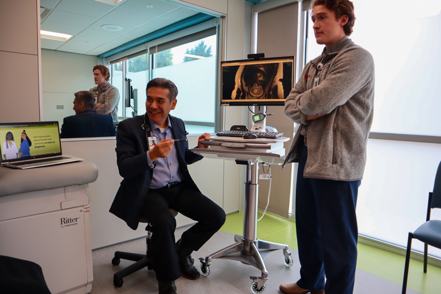 sitting man and standing man talk to family about image on monitor