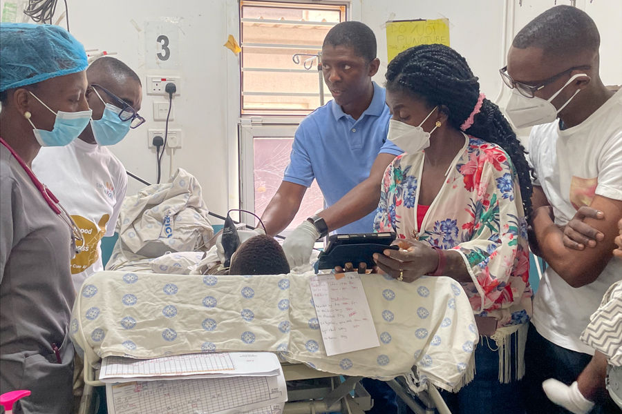 people standing around hospital bed looking at monitor equipment