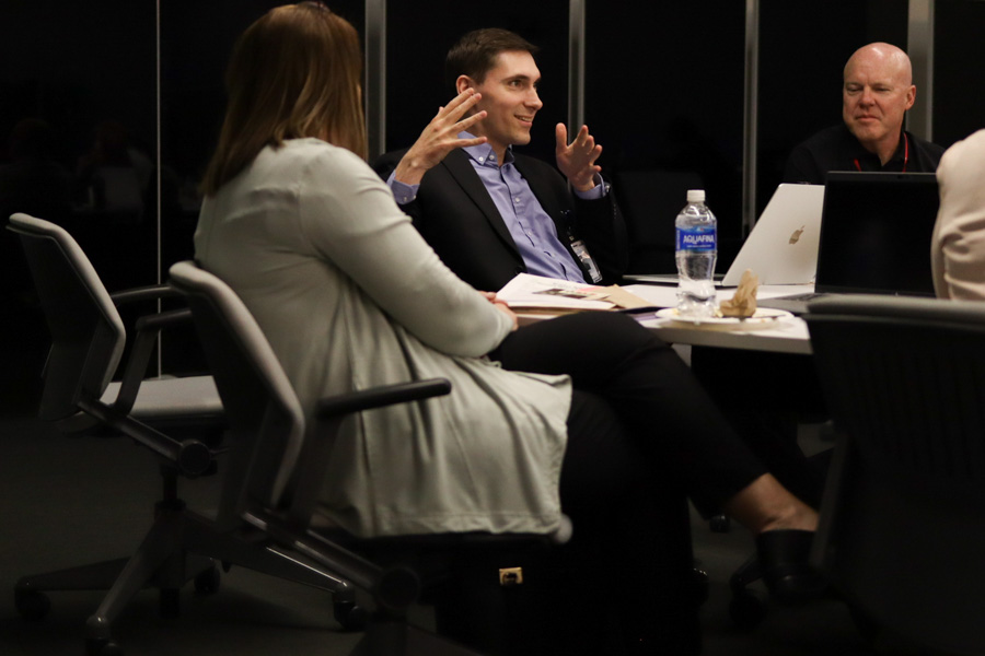 man talking at a table with other people listening 