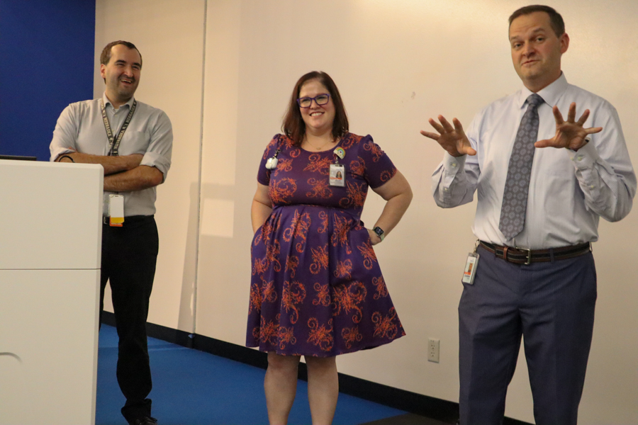 Two men and a woman talking at a podium