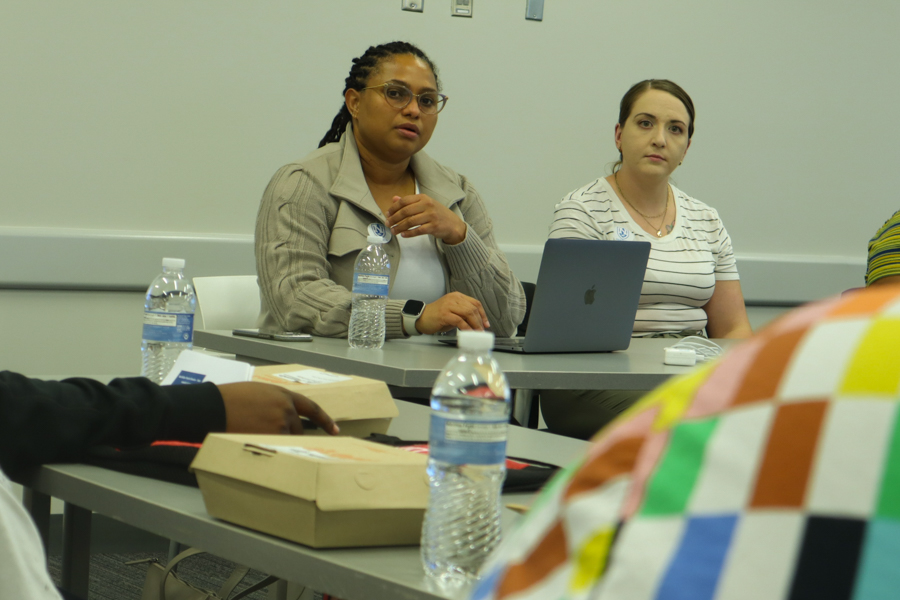 two women sitting at a table talking to group