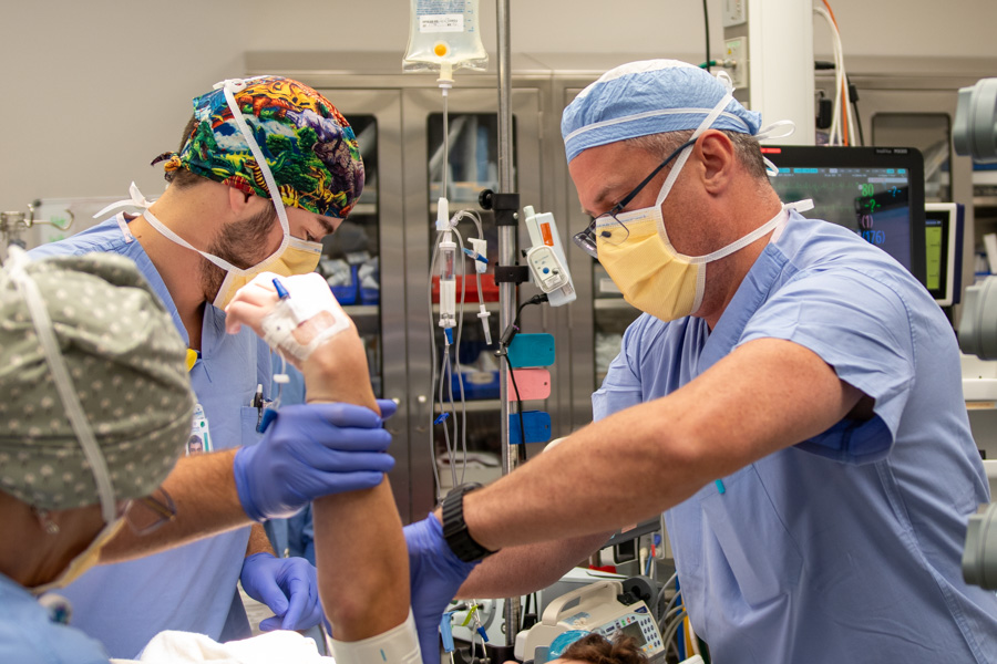 doctor holding up the arm of patient on operating table