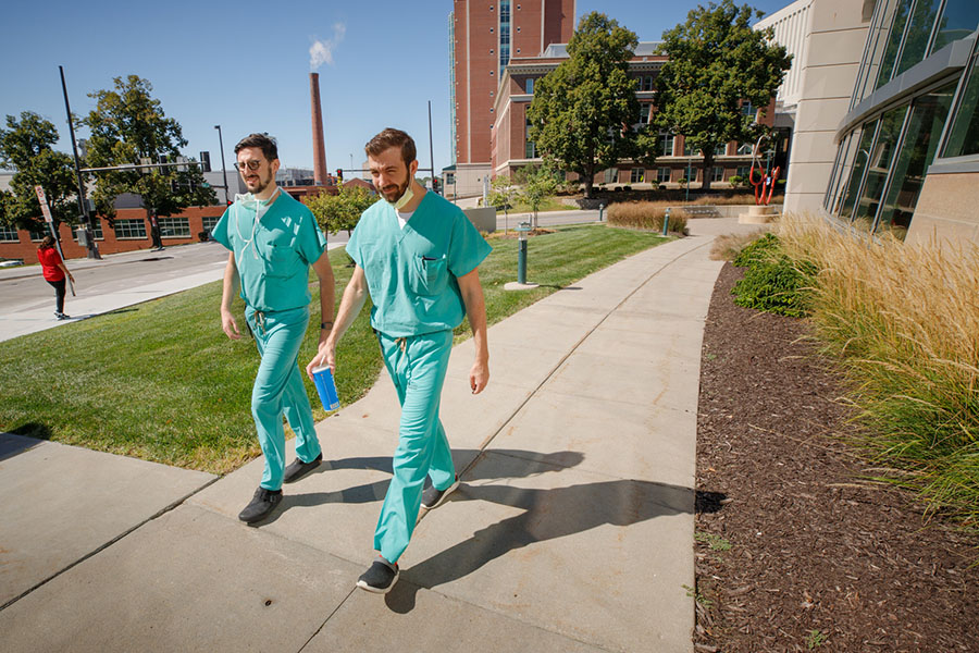 Two students wearing scrubs walk on UNMC's Omaha campus