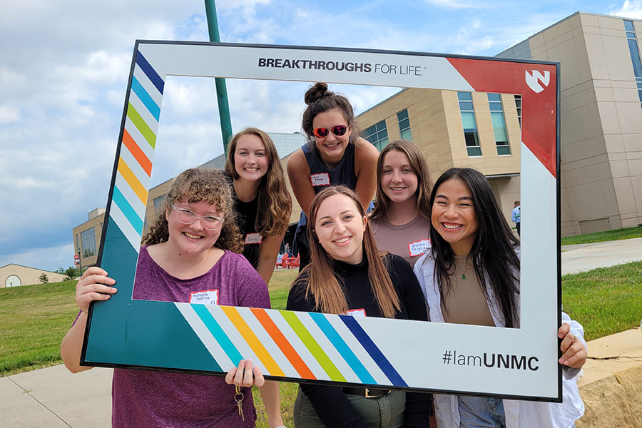 Students posing in an 'I am UNMC' frame