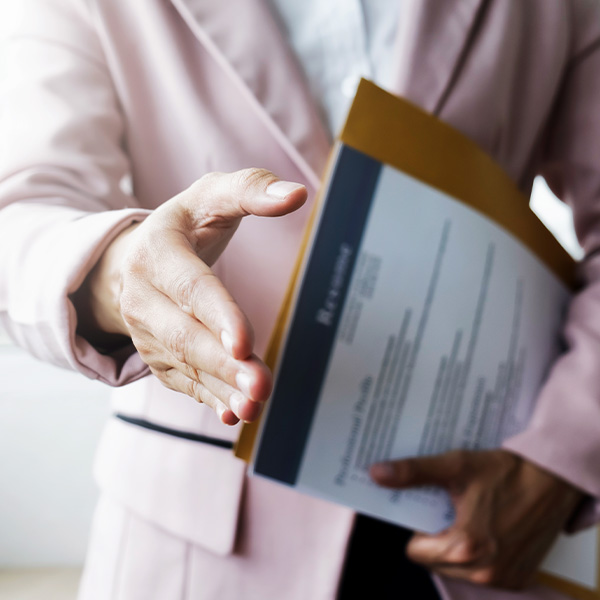 Job candidate holds out hand to shake interviewers hand