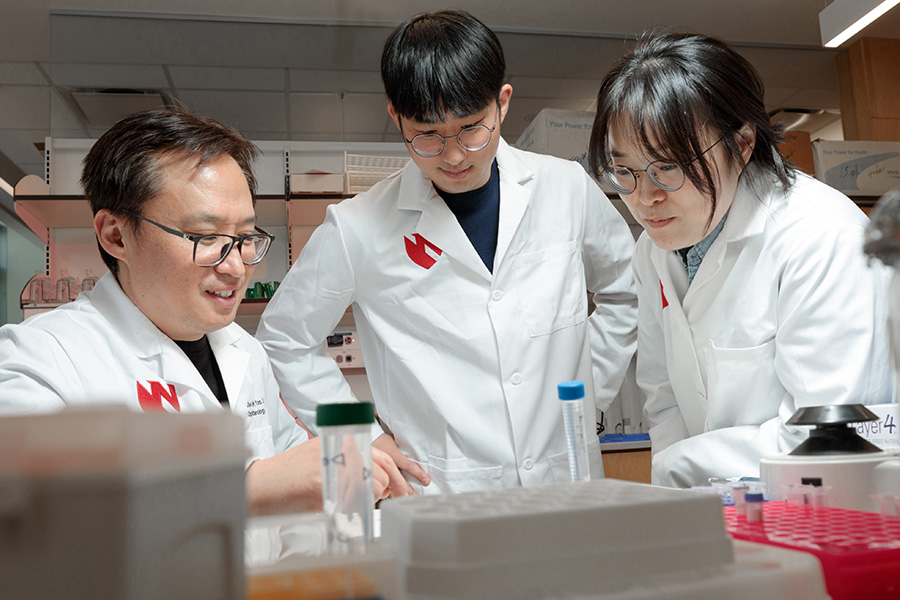 Mentor showing two postdocs something in the lab