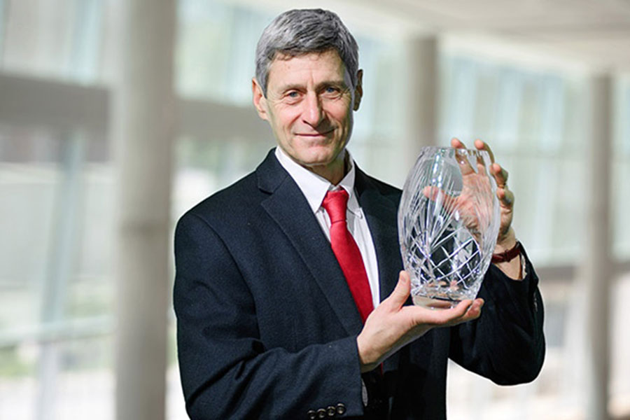 Distinguished scientist poses with their award