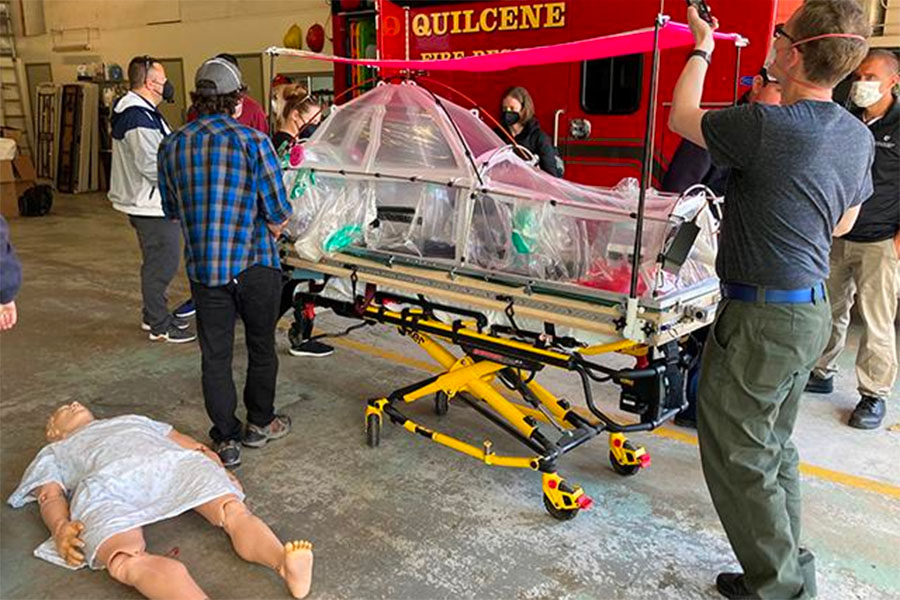 The patient-isolation system, atop a gurney, will be tested in a simulation involving a medical manikin.