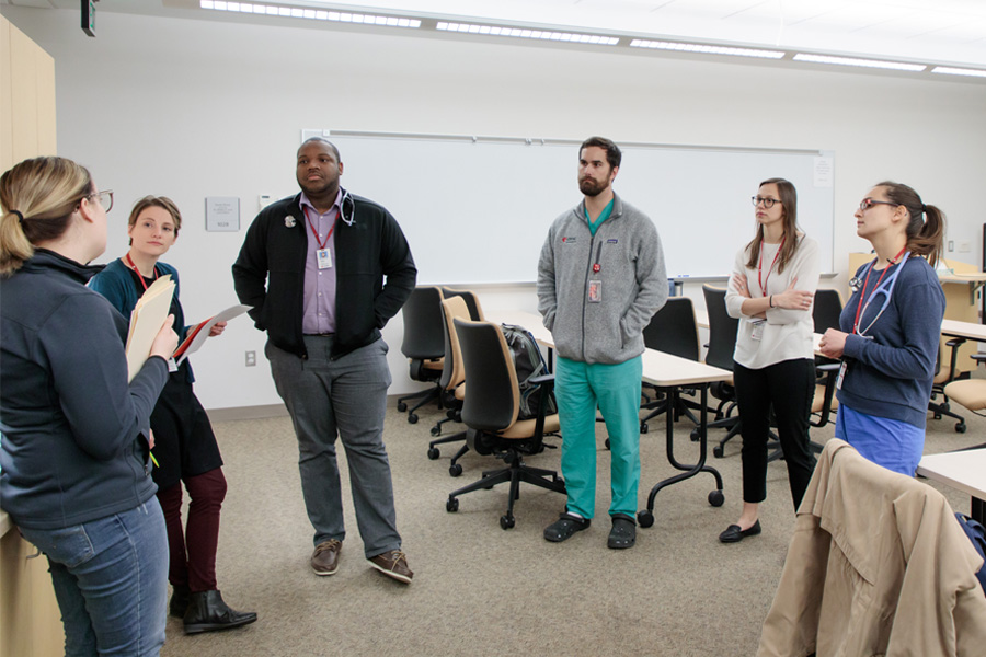 PhD students standing in a circle listening to a teacher