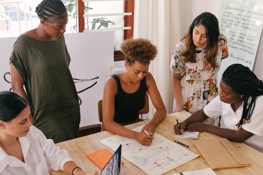 A group of people standing around a desk looking at documents.