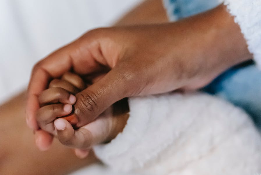 A hand holding an infants hand. 