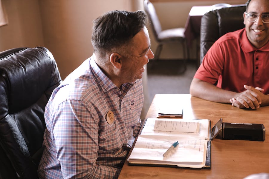 Two people sitting at a desk looking at paperwork.