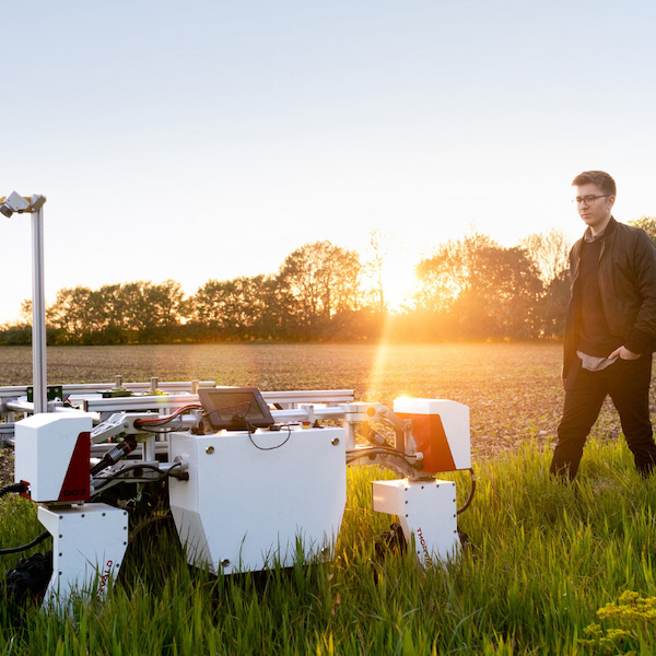 A person looking at a machine in a field.