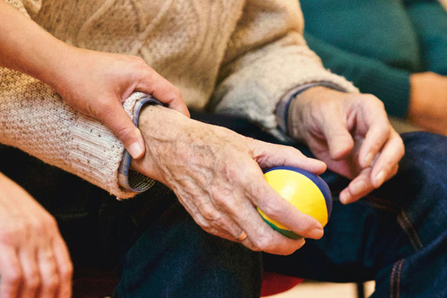 An elderly person holding a ball.