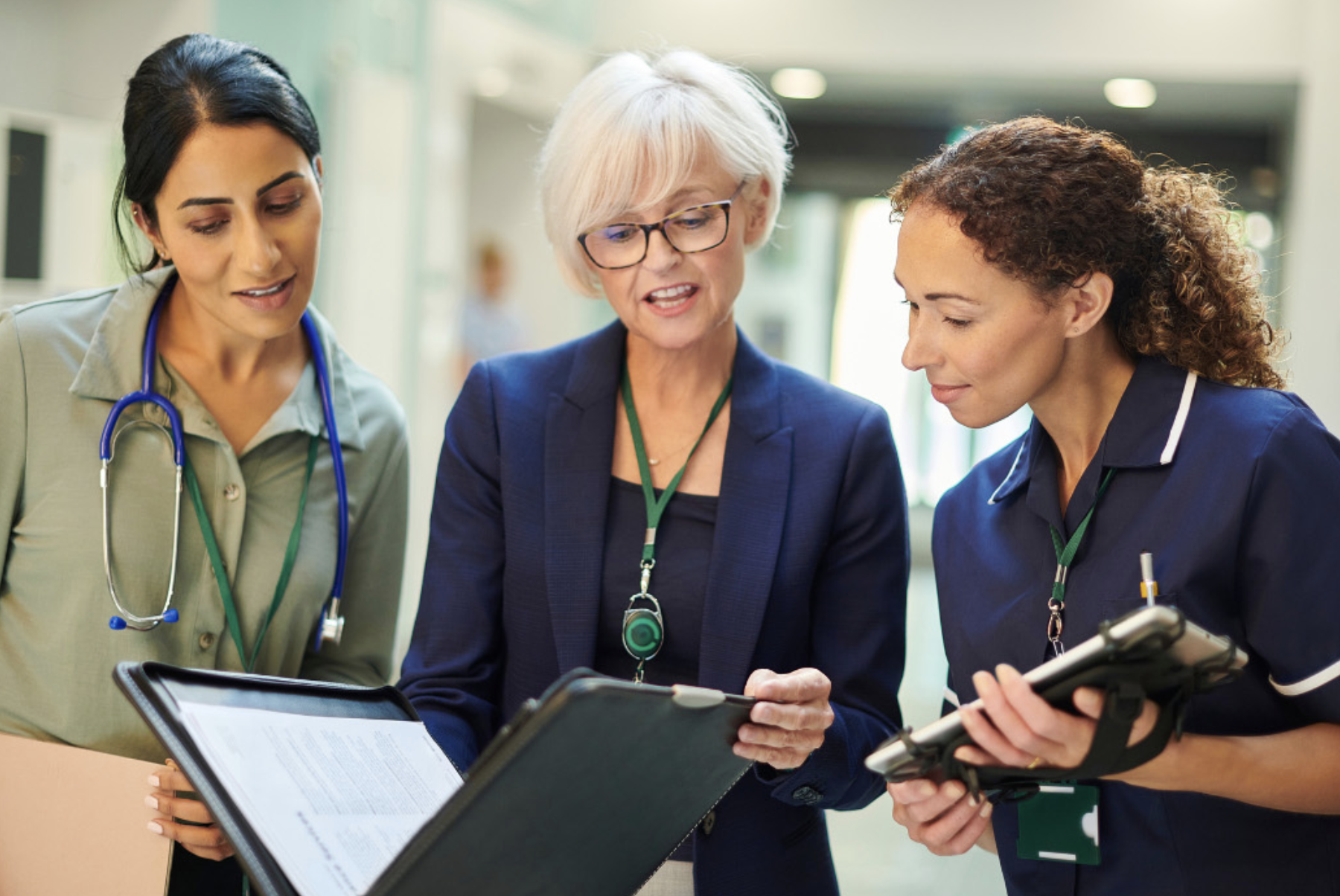 An administrator and two healthcare professionals looking at a binder.