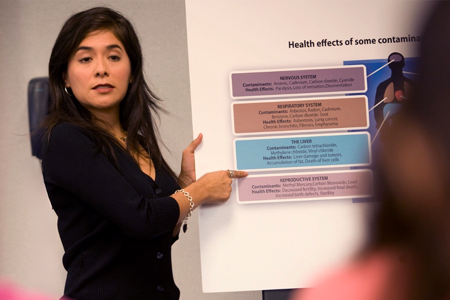 A professor standing at a podium in front of a PowerPoint.