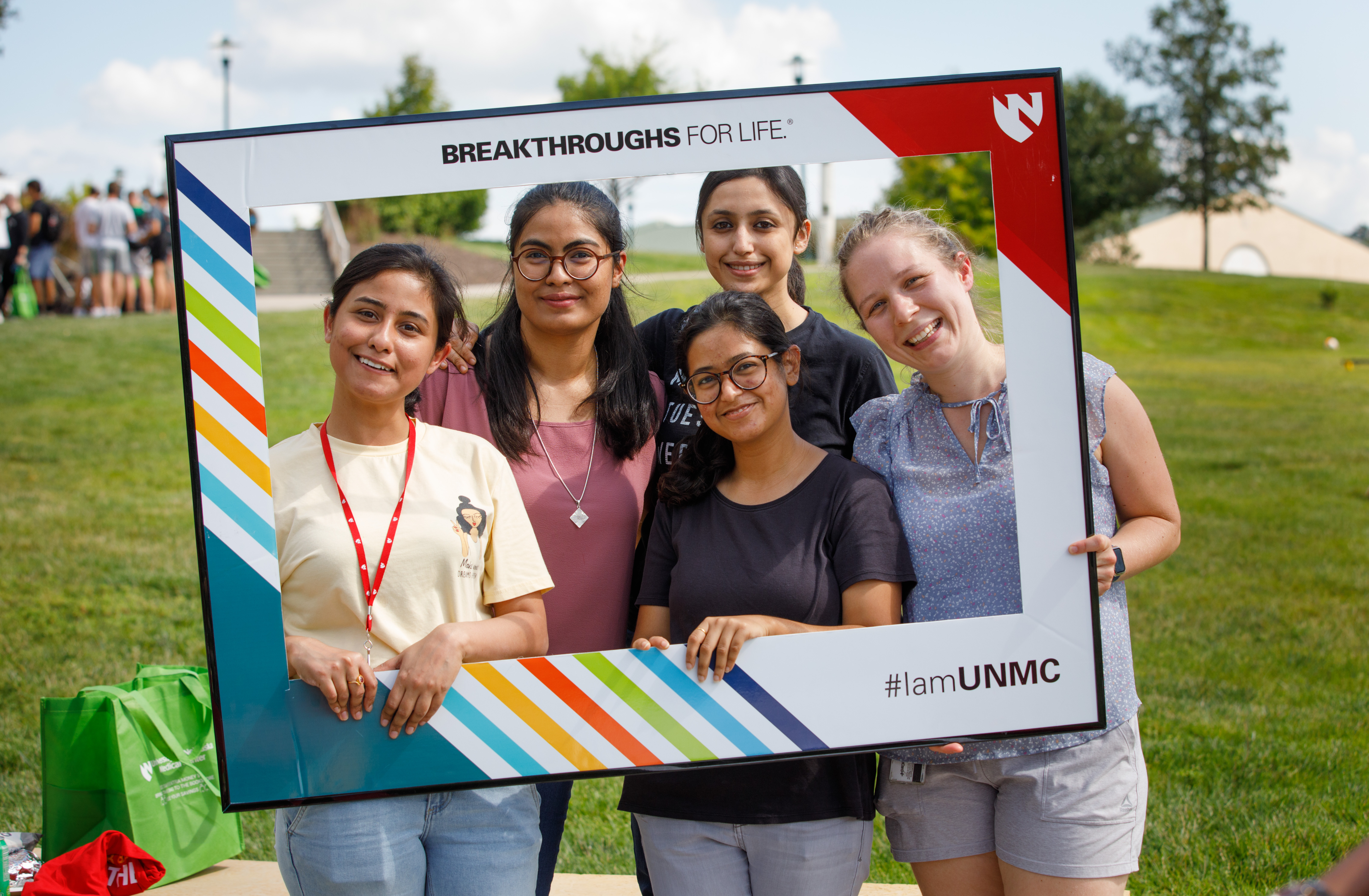 Image of four UNMC students with a UNMC sign.