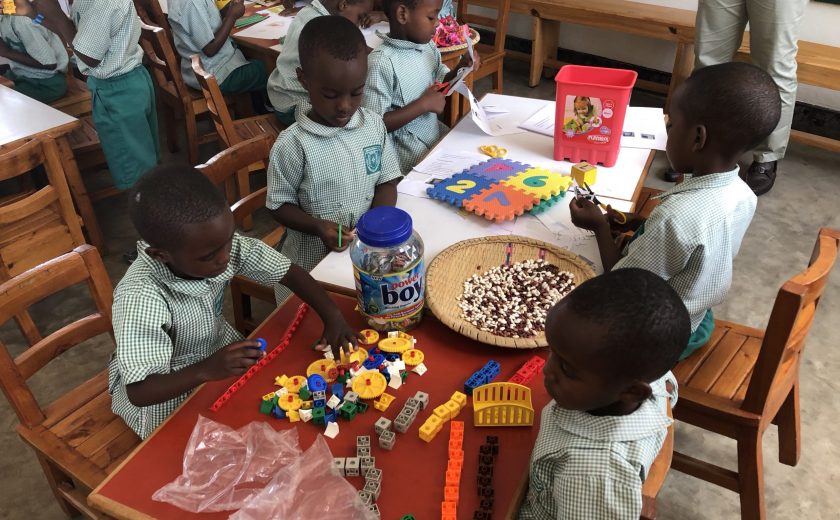 Image of young children in a classroom playing with blocks and making arts and crafts.