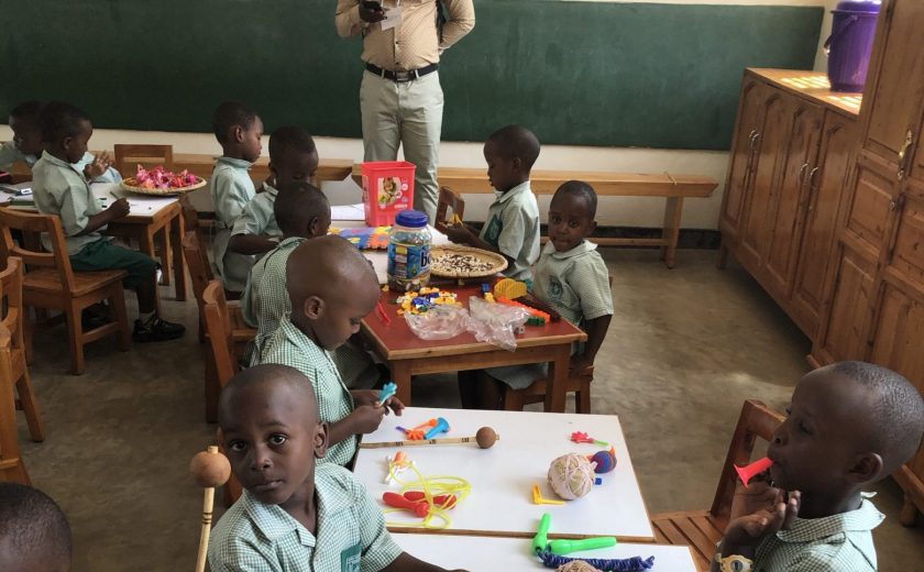 Young children in Rwanda making arts and crafts in a classroom.