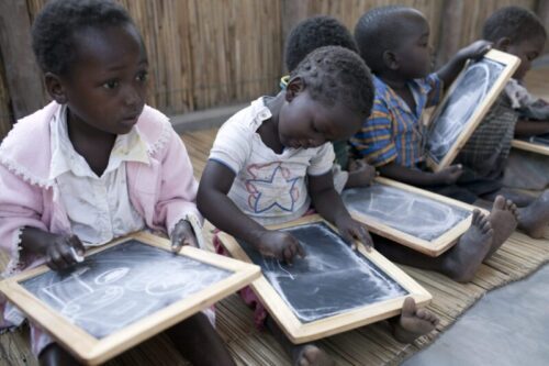Image of 4 young children writing on school chalk boards.