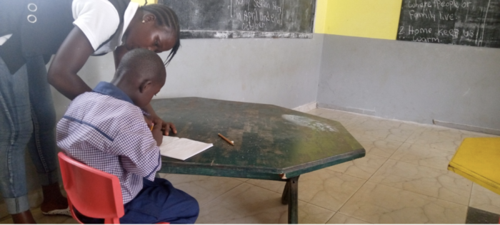 Image of a teacher helping a student at a school desk.