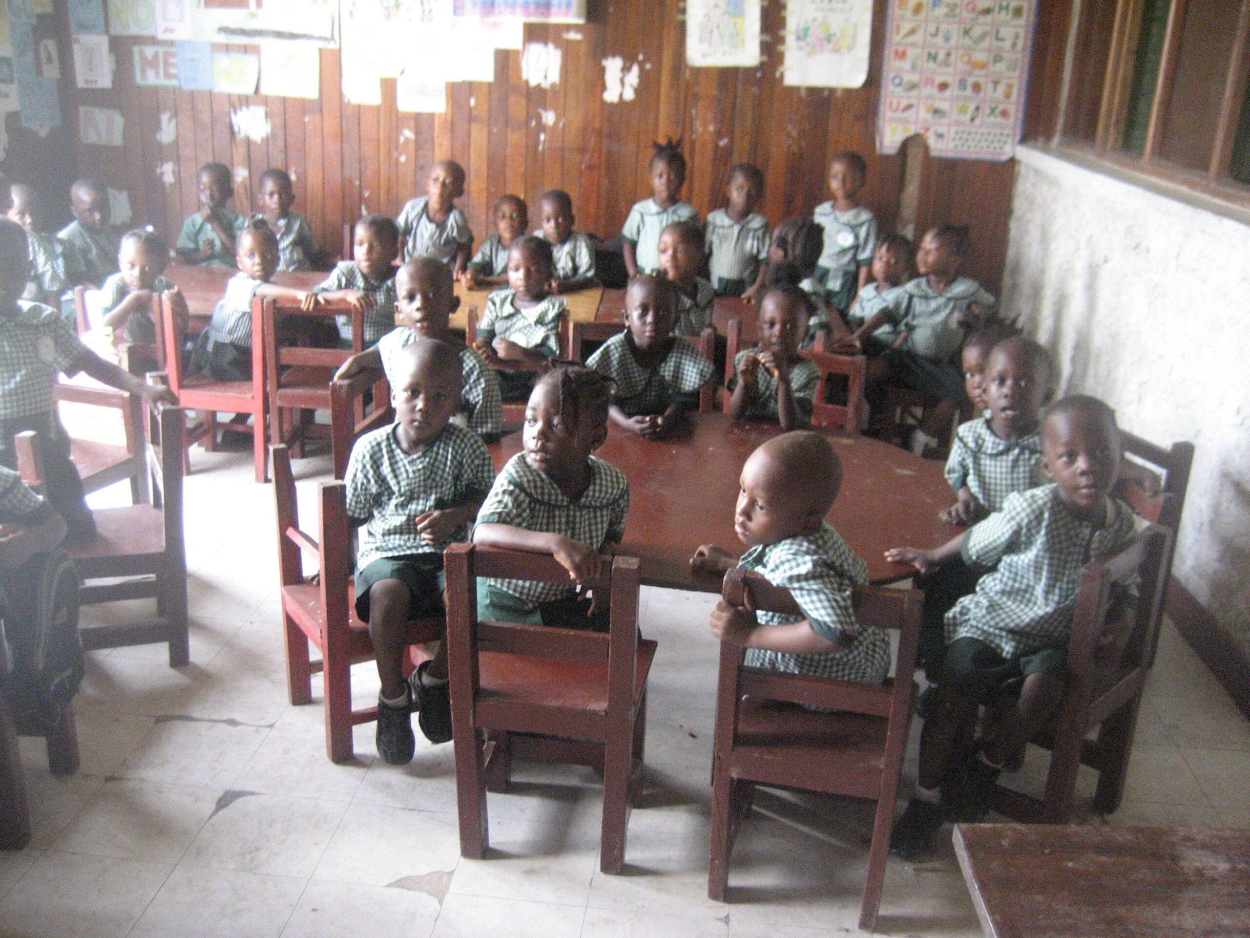 classroom of children in Liberia sitting around tables
