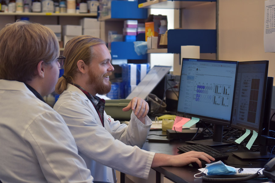 Two researchers view work on a computer screen