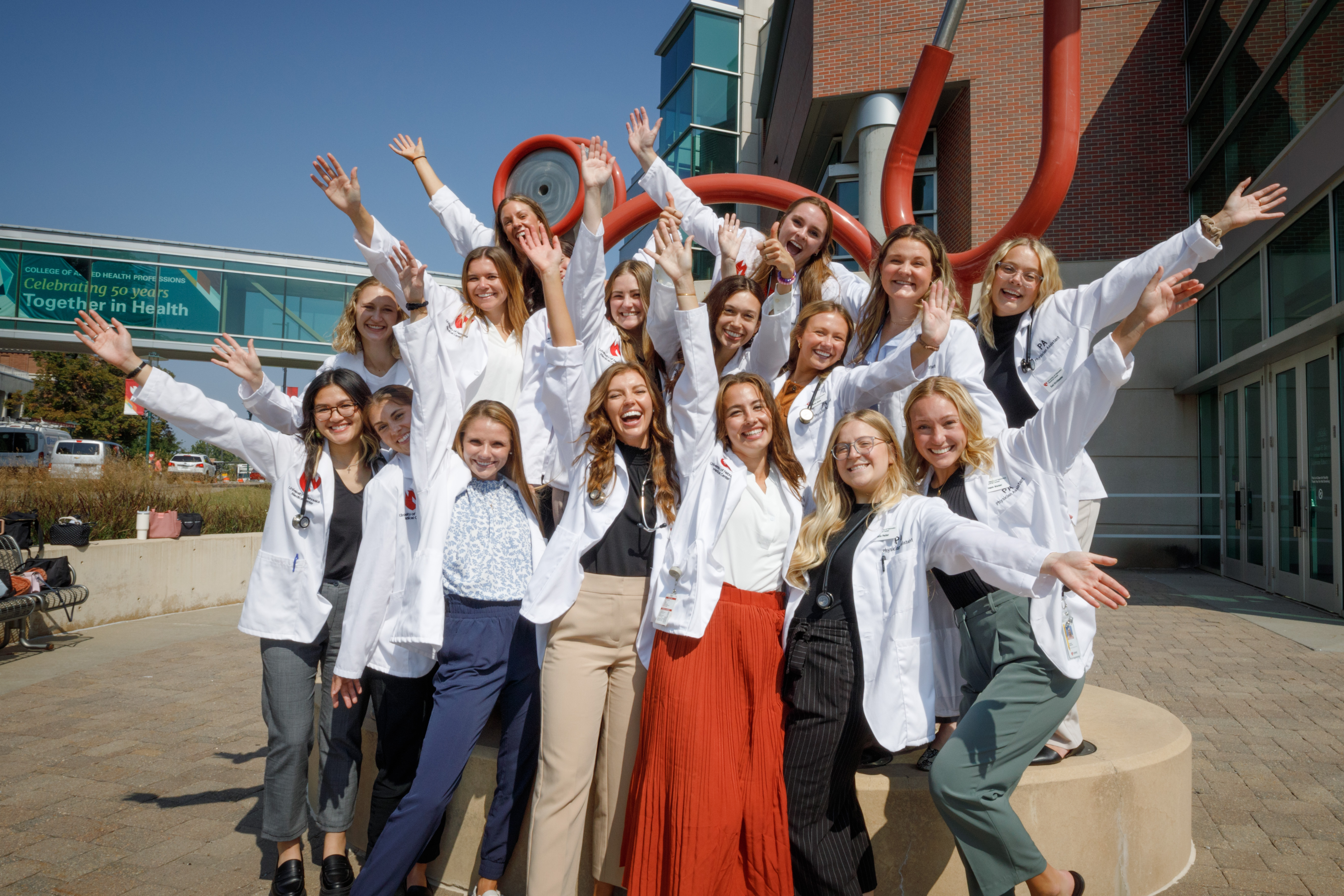 A group of students stand near a sculpture of a stethoscope