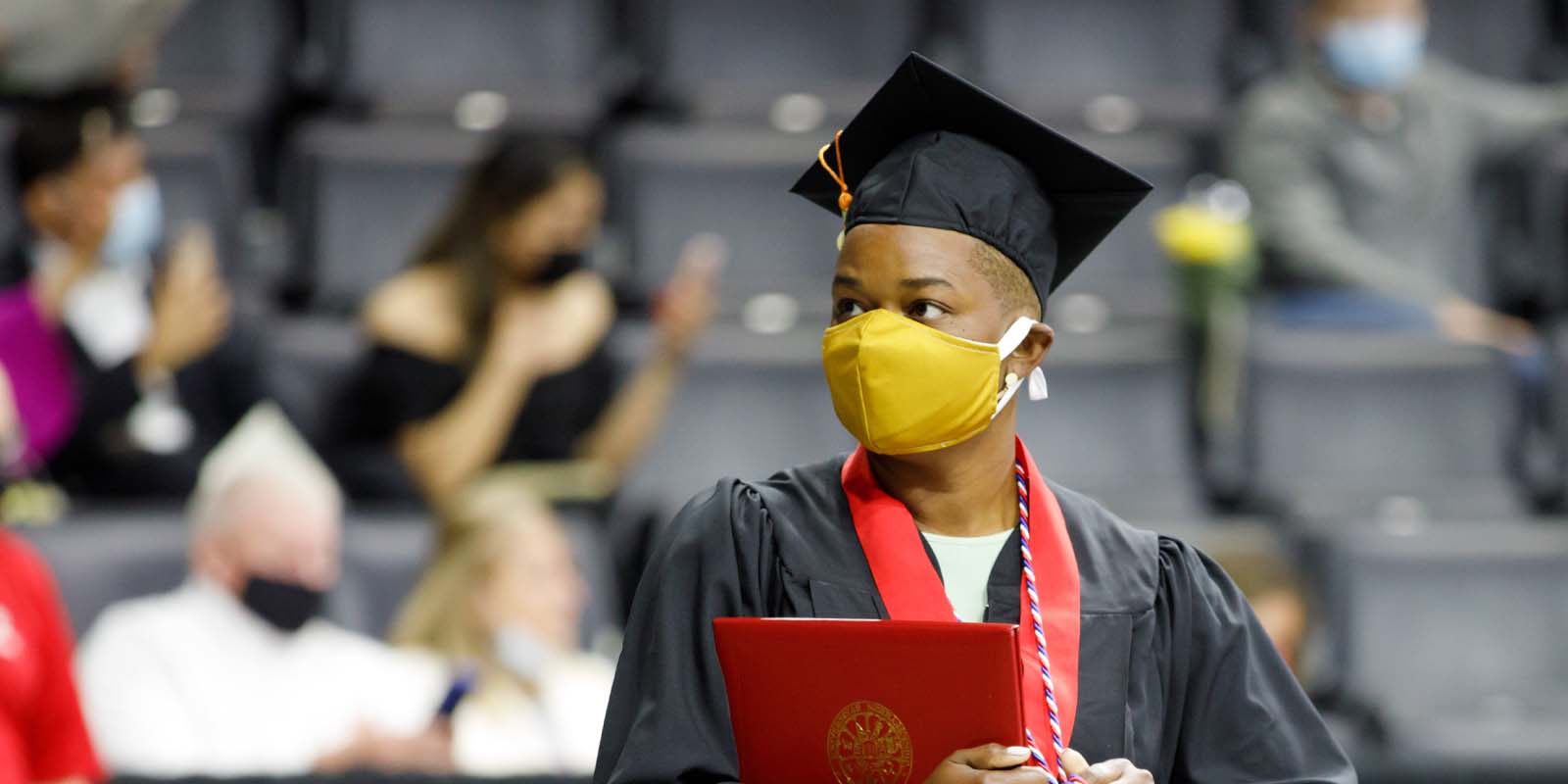 A woman in graduation attire holding a diploma