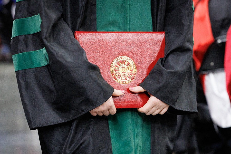 a graduate holds a UNMC diploma at commencement