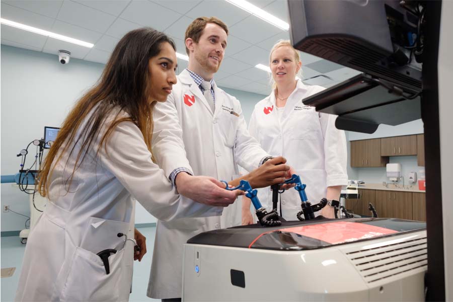 A group of three medical students gather around a computer