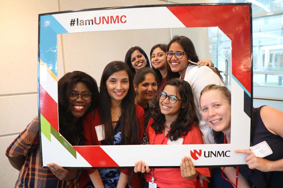 Eight female graduate students pose in a branded frame