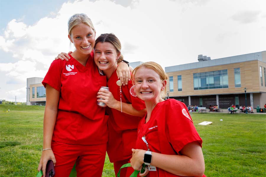 Three UNMC nursing students embrace outside an academic building