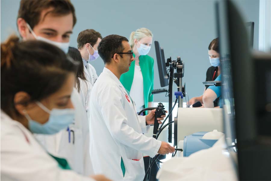 Students in white coats work at computers