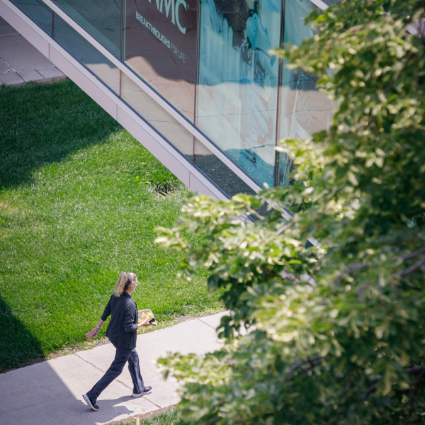 A person walks underneath a skywalk with a UNMC banner in the window