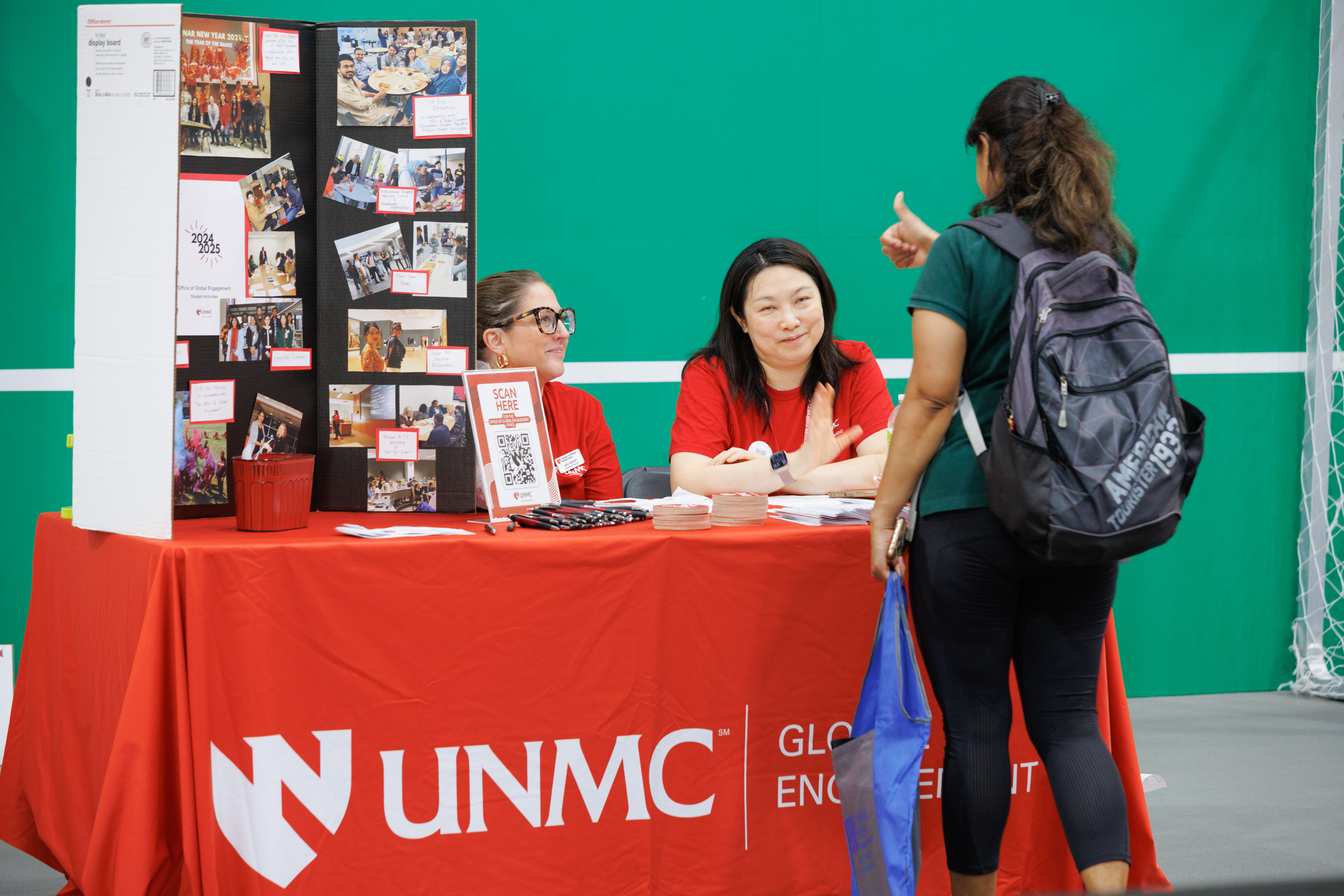 Office of Global Engagement members talk to a student at their informational table at the involvement fair