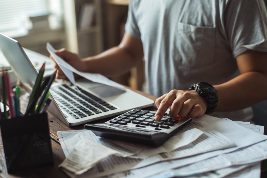student with a calculator, receipts, and computer