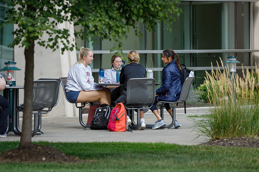 four students sit at a table outside the Durham Research Center