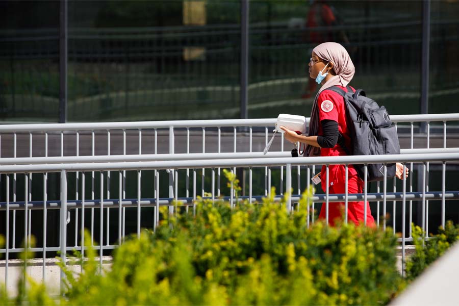 A nursing student with a head wrap walks outside on UNMC's campus