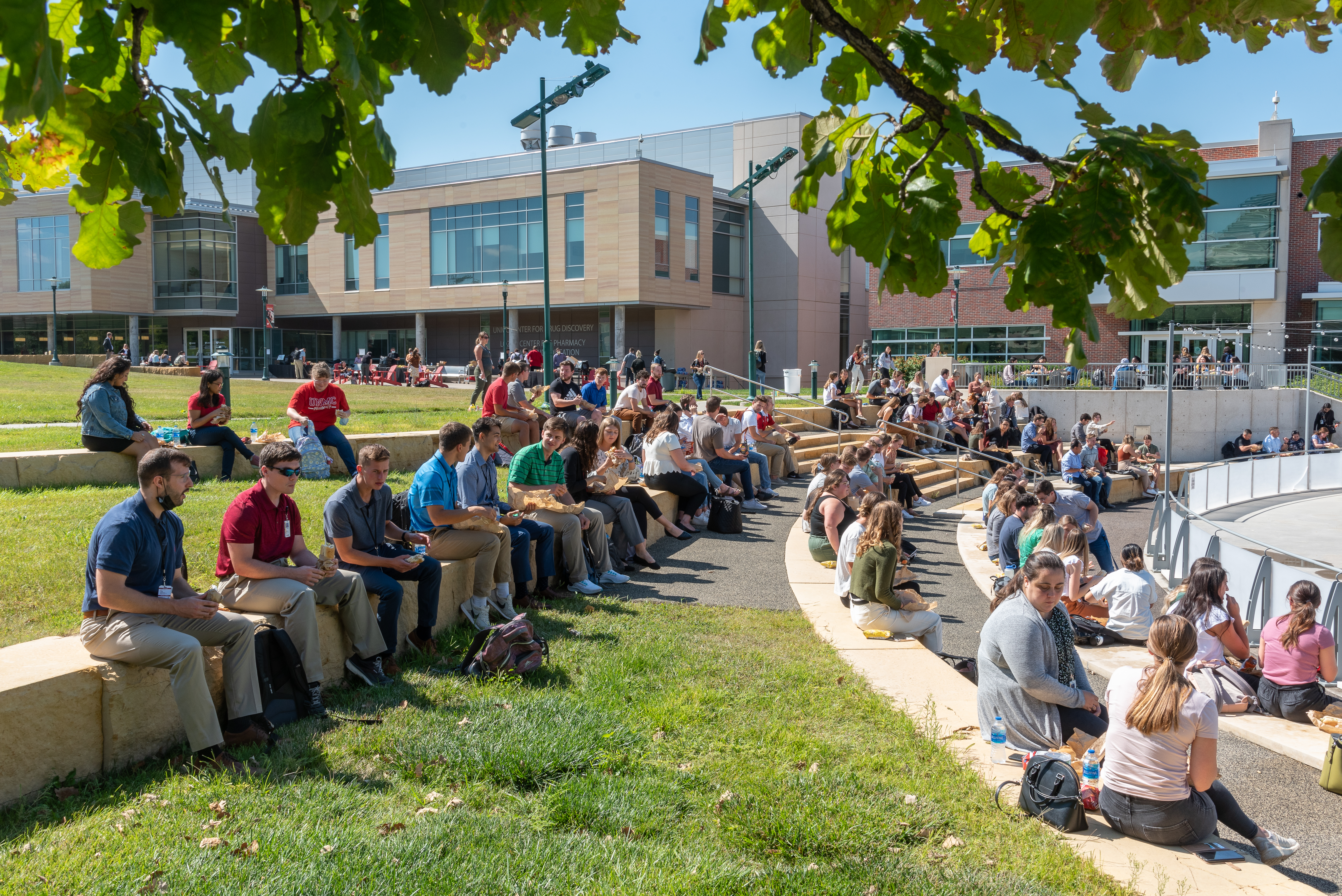 a group of students sit on the terraced landings by the ice rink during orientation activities