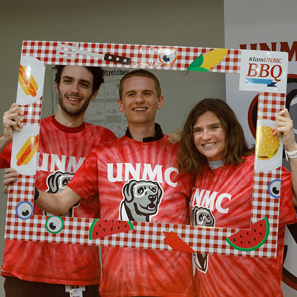 three students pose inside a cutout picture frame at the UNMC back-to-school barbeque